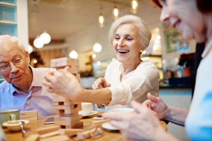 Mature people enjoying jenga game in cafe